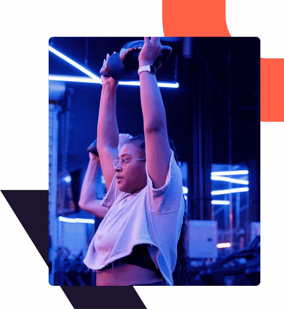 Woman lifting a kettlebell overhead in a gym with blue neon lights.