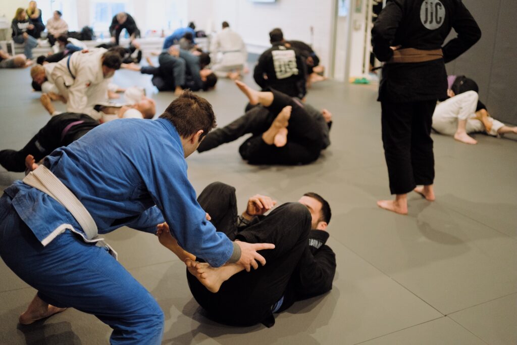 Jiu-jitsu students practice grappling techniques on mats in a gym